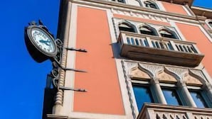 A building with a clock, ornate balconies, and a clear blue sky. - Vista Palazzo, Lago di Como (Como)
