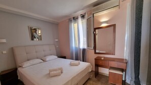 Ein Hotelzimmer mit einem großen Bett, einem Nachttisch, einem Spiegel und einem Fenster mit Vorhängen.