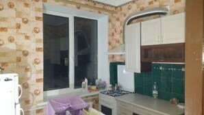 A kitchen with a window, white cabinets, a stove, and a sink. - Yourhostel Pechersk (Kyiv)