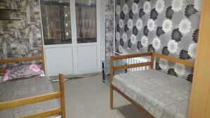 A room with two wooden bunk beds, a window with a view of buildings, and a patterned wallpaper. - Yourhostel Pechersk (Kyiv)