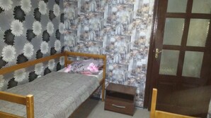 A small room with a single bed, a wooden nightstand, and a door with frosted glass panels. - Yourhostel Pechersk (Kyiv)