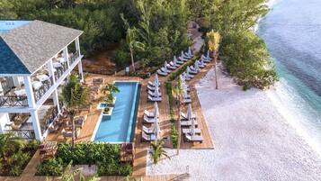 Vista aérea de un resort con piscina, tumbonas y una playa.