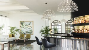 A modern bar area with a curved counter, two black bar stools, and a large selection of bottles.