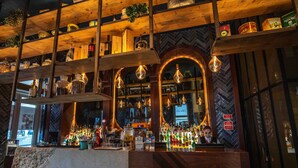 A bar area with shelves of bottles, a bartender, and a herringboard. - My Story Hotel Figueira (Lisbon)