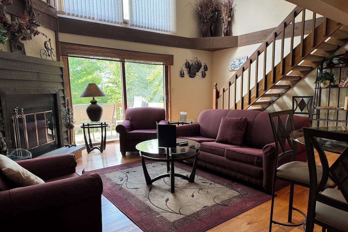 Un salon avec une cheminée, un canapé, une table basse et un escalier.