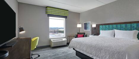 Ett hotellrum med en säng, ett skrivbord, en stol, ett fönster och utsikt över omgivningarna.