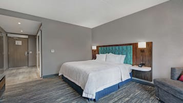 Une chambre d’hôtel avec un grand lit, une table de chevet, une chaise et une porte donnant sur une salle de bain.