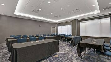 A conference room with tables and chairs, a carpeted floor, and a large window.