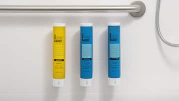 Trois bouteilles de gel douche sont accrochées à un mur.