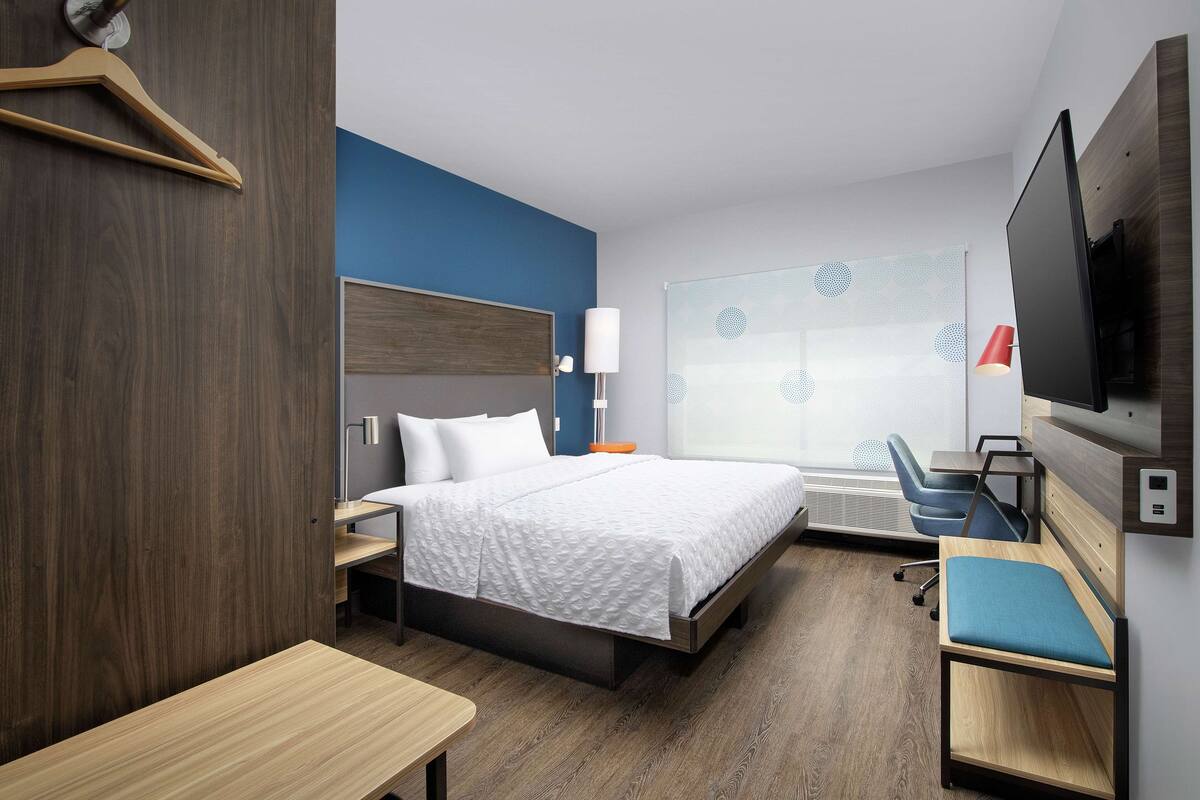 Ein modernes Hotelzimmer mit Bett, Schreibtisch, Stuhl, Fernseher und einem Fenster mit Blick.