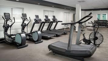 Un gimnasio con cintas de correr, bicicletas estáticas y una máquina de remo.