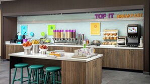 A breakfast area with a counter, stools, and various food dispensers. - Tru by Hilton San Antonio Lackland Sea World (San Antonio)