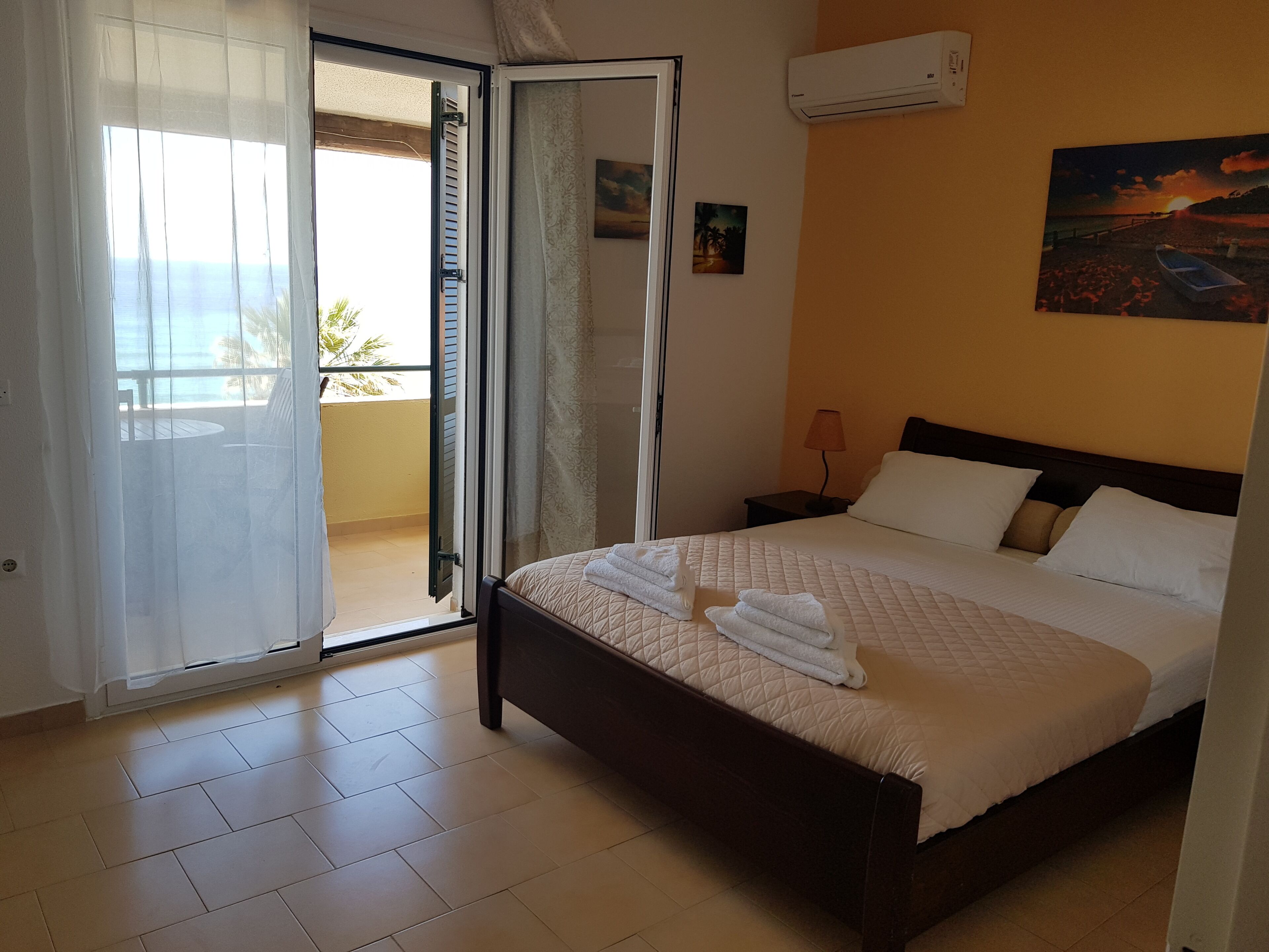 Una habitación de hotel con cama, mesita de noche, lámpara y un cuadro en la pared.