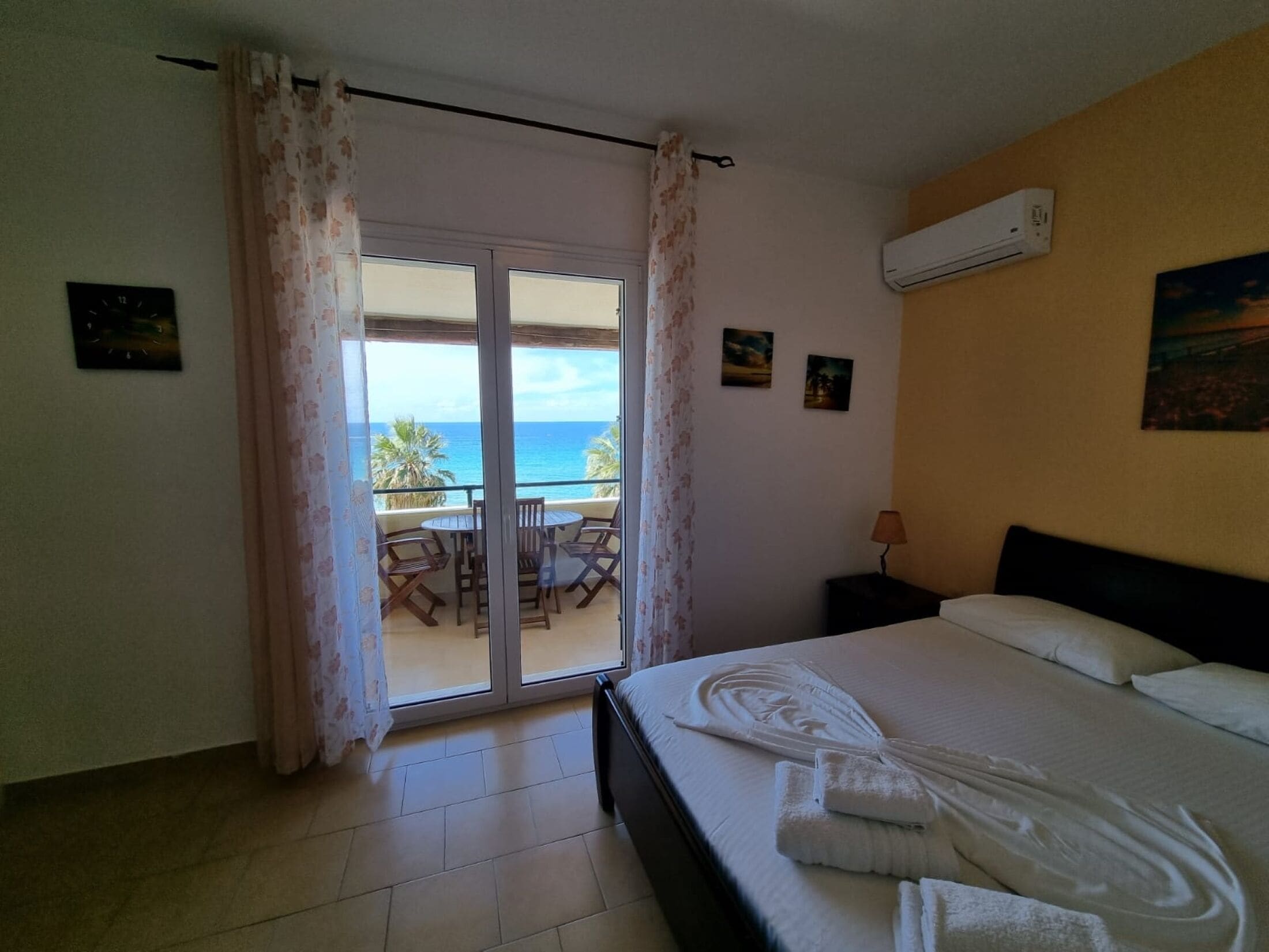Une chambre d’hôtel avec un lit, une petite table et une vue sur l’océan, accessible par une porte coulissante.