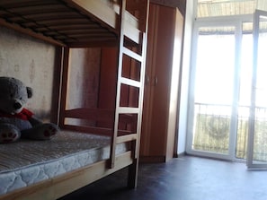 A bunk bed with a ladder, a teddy bear, and a sliding glass door leading to an outdoor area. - Yourhostel La Femme (Kyiv)
