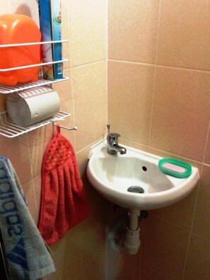 A bathroom with a sink, a towel rack with a red towel, and a shelf with toiletries. - Yourhostel La Femme (Kyiv)