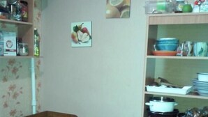 A dining area with a wooden table and benches, surrounded by shelves with kitchenware and food items. - Yourhostel La Femme (Kyiv)