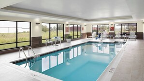 Una piscina interior amb parets de vidre transparent, una posta de socors i un elevador de piscina.