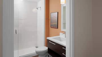 A modern bathroom with a glass shower enclosure, a white toilet, and a vanity with a mirror.