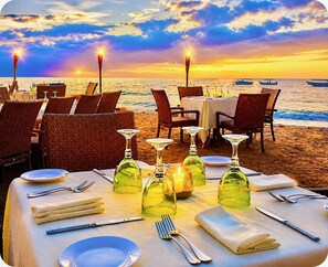 A beachside restaurant with tables set for dining, overlooking the ocean.