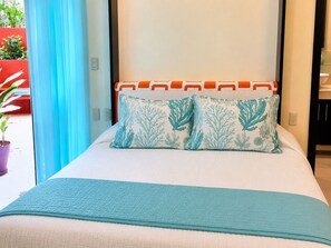 A bed with a white headboard, two decorative pillows, and a teal bedspread.