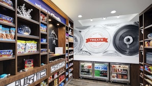 A store with shelves stocked with snacks and beverages, a 'Welcome to' sign, and a large wall with a 'Treats' sign. - Hampton Inn & Suites D'Iberville Biloxi (D'Iberville)