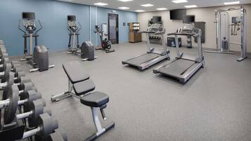 Een sportschool met loopbanden, elliptische trainers en losse gewichten.