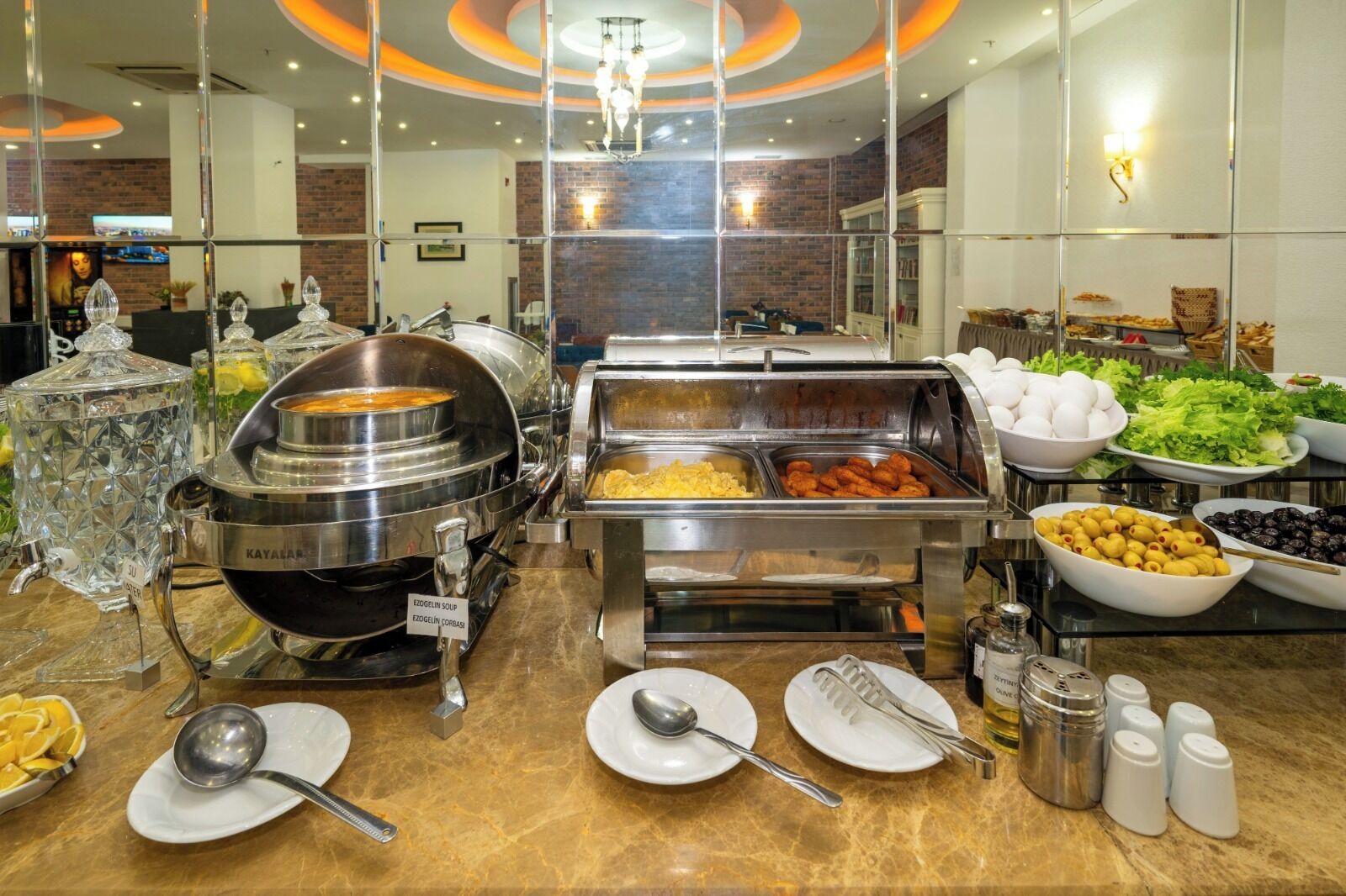 Un bufé con diversas opciones de comida, como sopa, huevos y aceitunas.