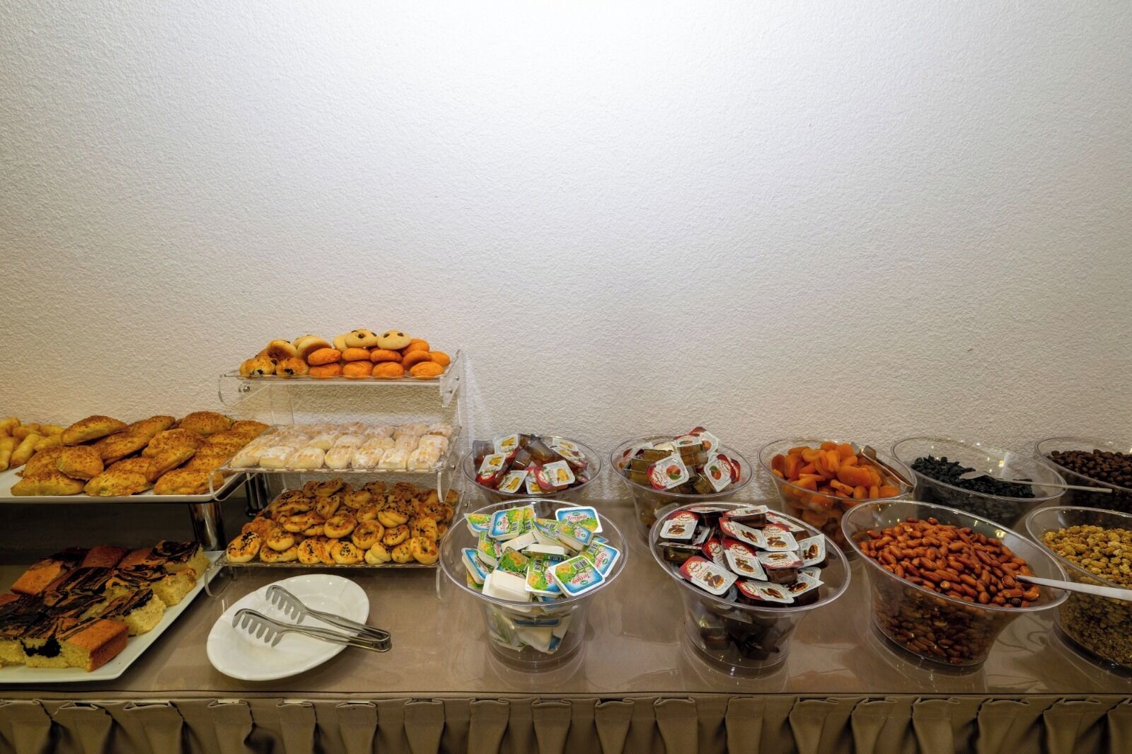 A buffet with various food items including pastries, cookies, and nuts.