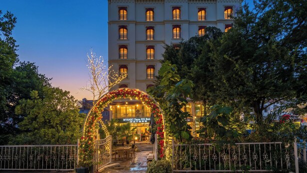 A hotel entrance with a decorative archway, a sign indicating the hotel name, and a view of the building's facade. - Kunlun Kensington Hotel (Istanbul)