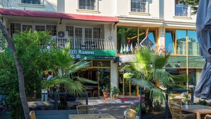 A restaurant with outdoor seating, a signboard, and potted plants. - Kunlun Kensington Hotel (Istanbul)