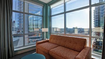 Una habitación de hotel moderna con un ventanal grande, un sofá y una pequeña mesa.