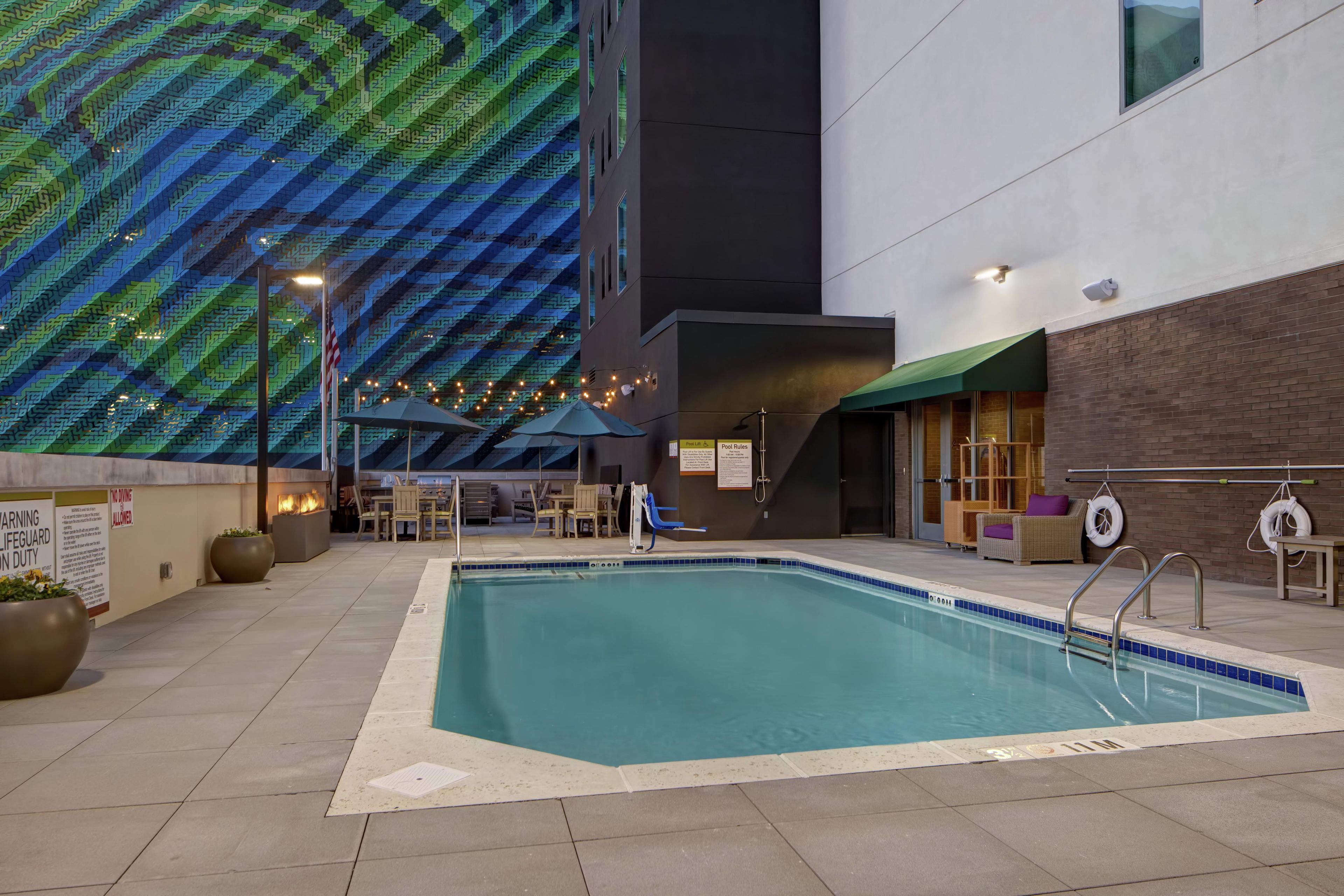 Una piscina interior con borde de azulejos, rodeada de sillas de descanso y sombrillas.