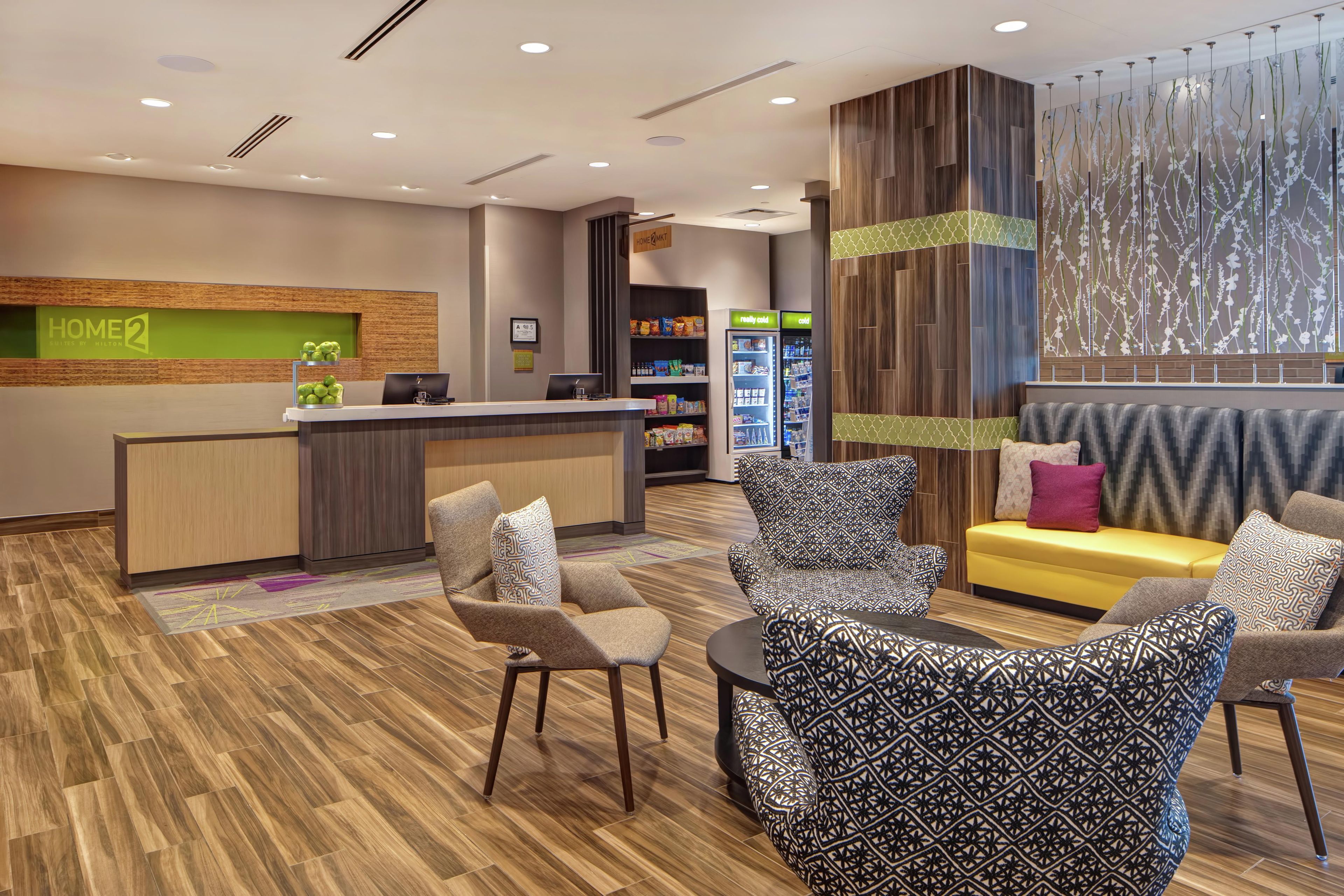 A hotel lobby with a reception desk, seating area, and a wall with a decorative panel.