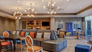 A modern lounge area with a large seating area, a dining table, and a television.