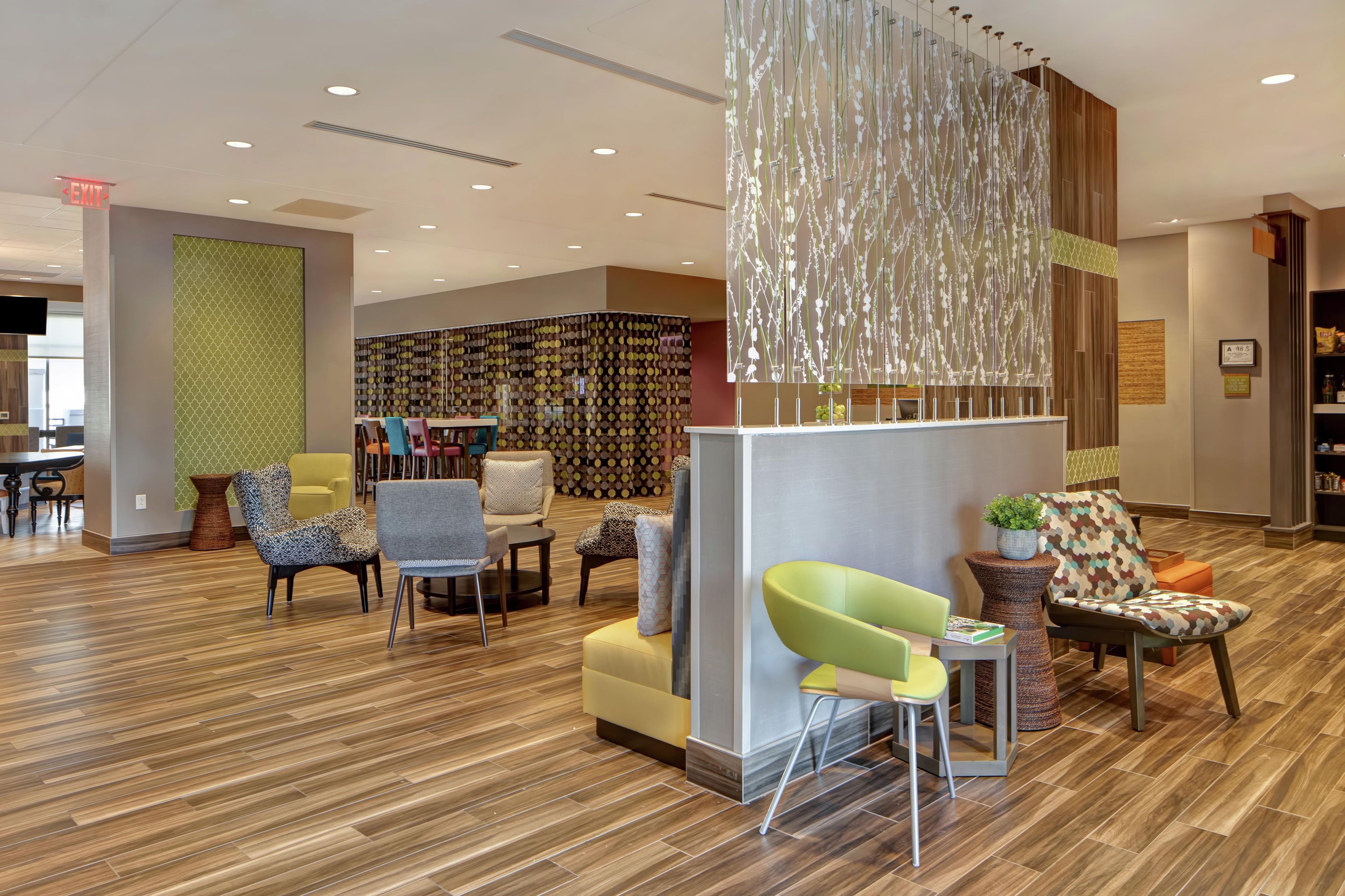 A modern lobby with a reception desk, seating area, and a patterned wall.