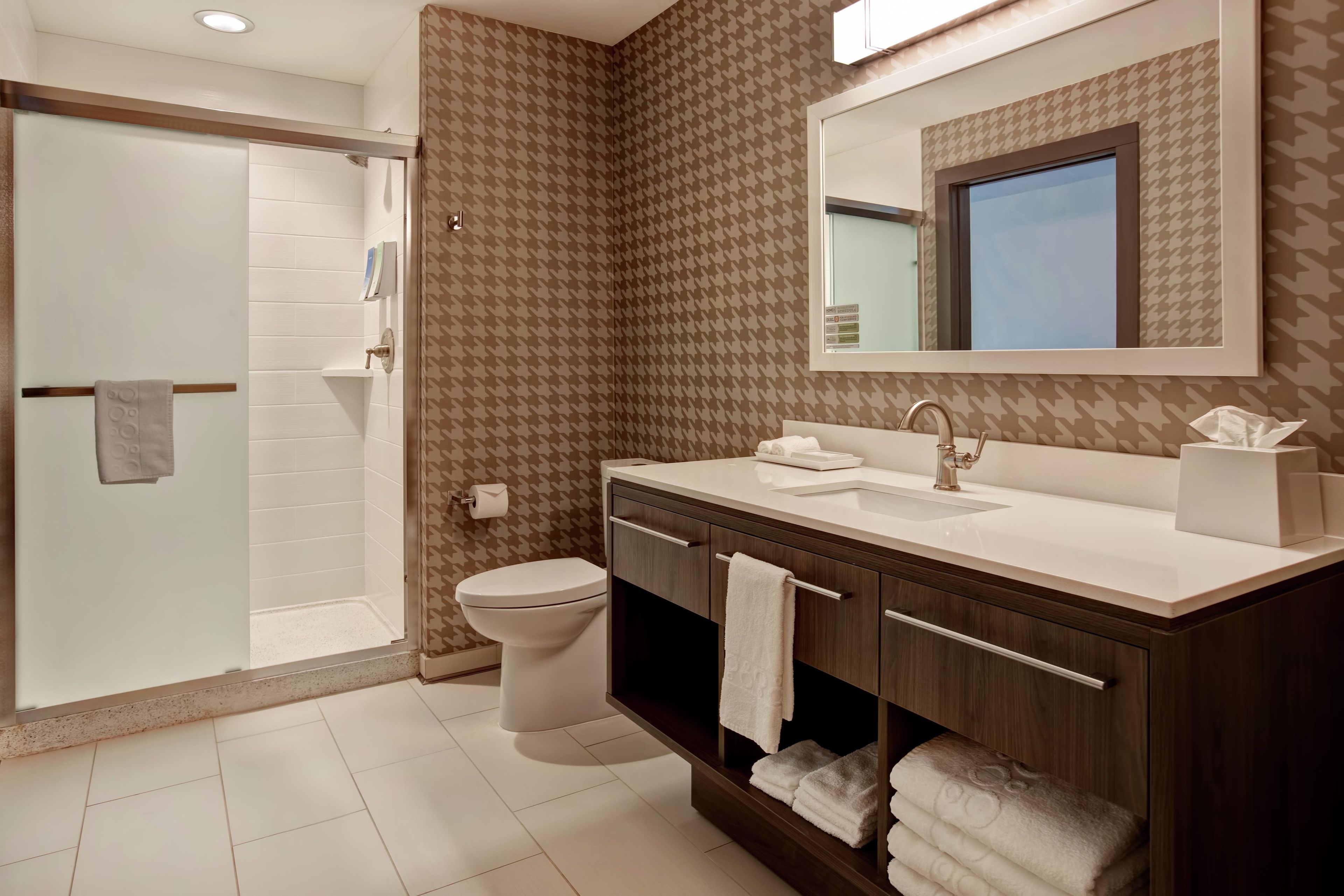 A modern bathroom with a shower, toilet, and vanity with a mirror.