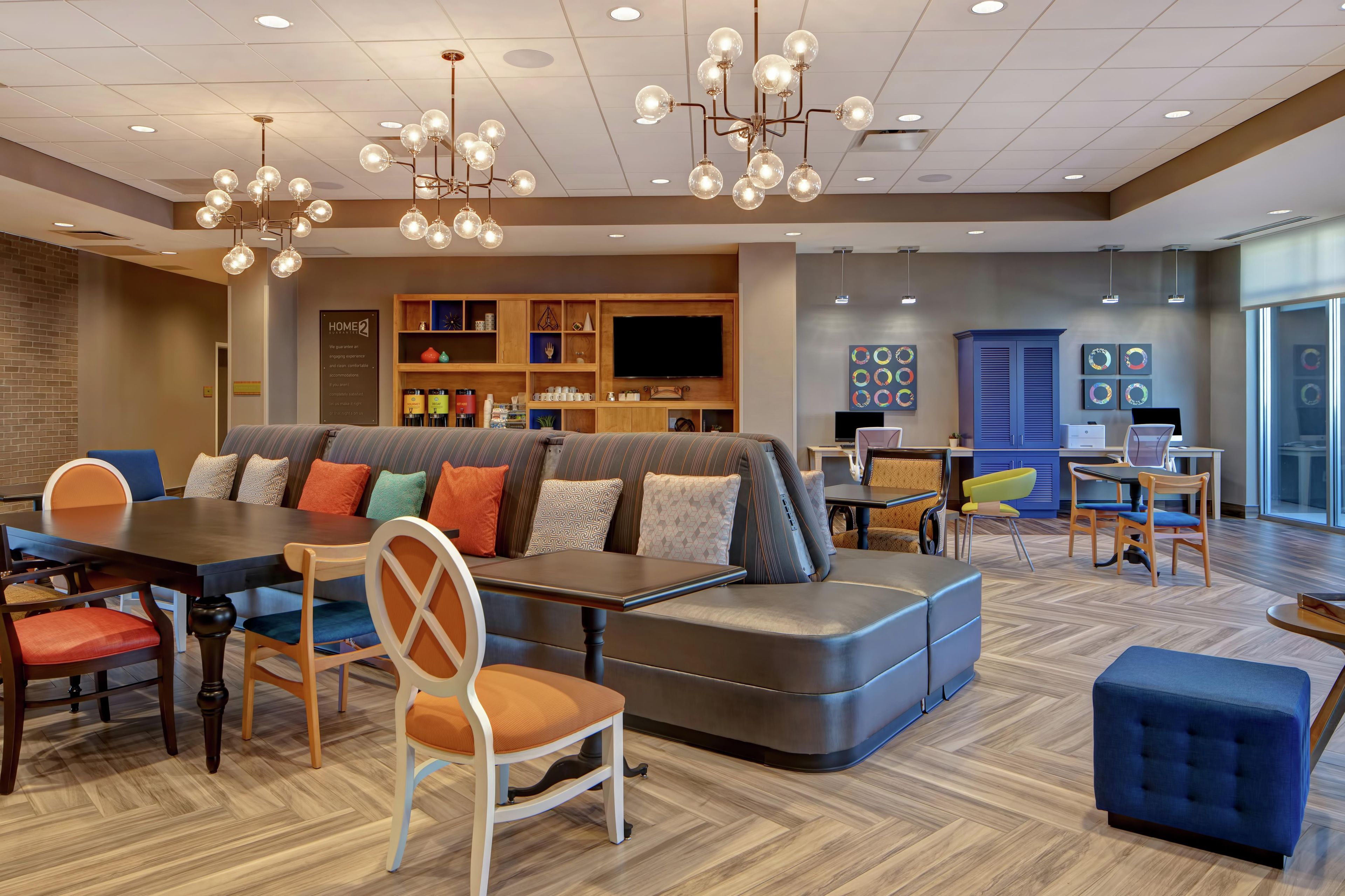 A modern hotel lobby with a seating area, a dining table, and a television.