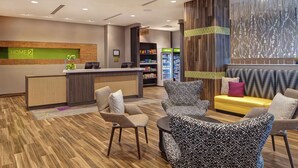 A hotel lobby with a reception desk, seating area, and a vending machine.