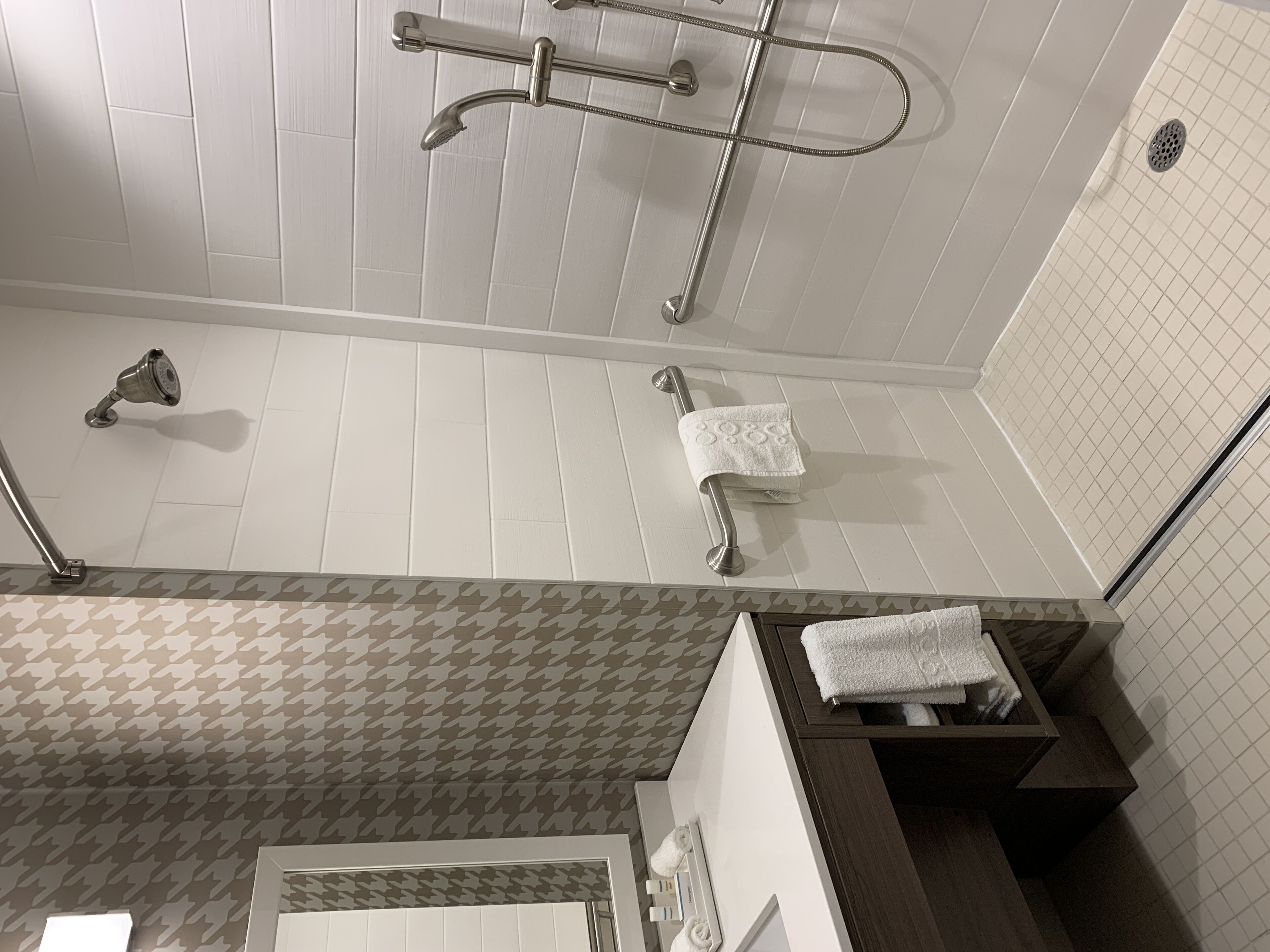 Un baño moderno con ducha, toallero y suelo estampado.