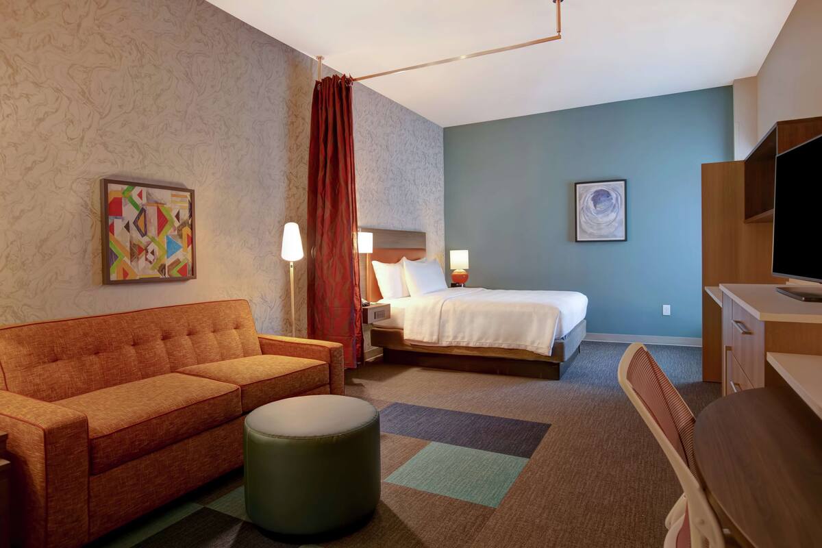 Une chambre d’hôtel avec un lit, un canapé, un bureau et une télévision.