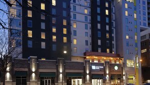 A multi-story hotel with a modern facade, a visible bank branch, and a well-lit entrance.