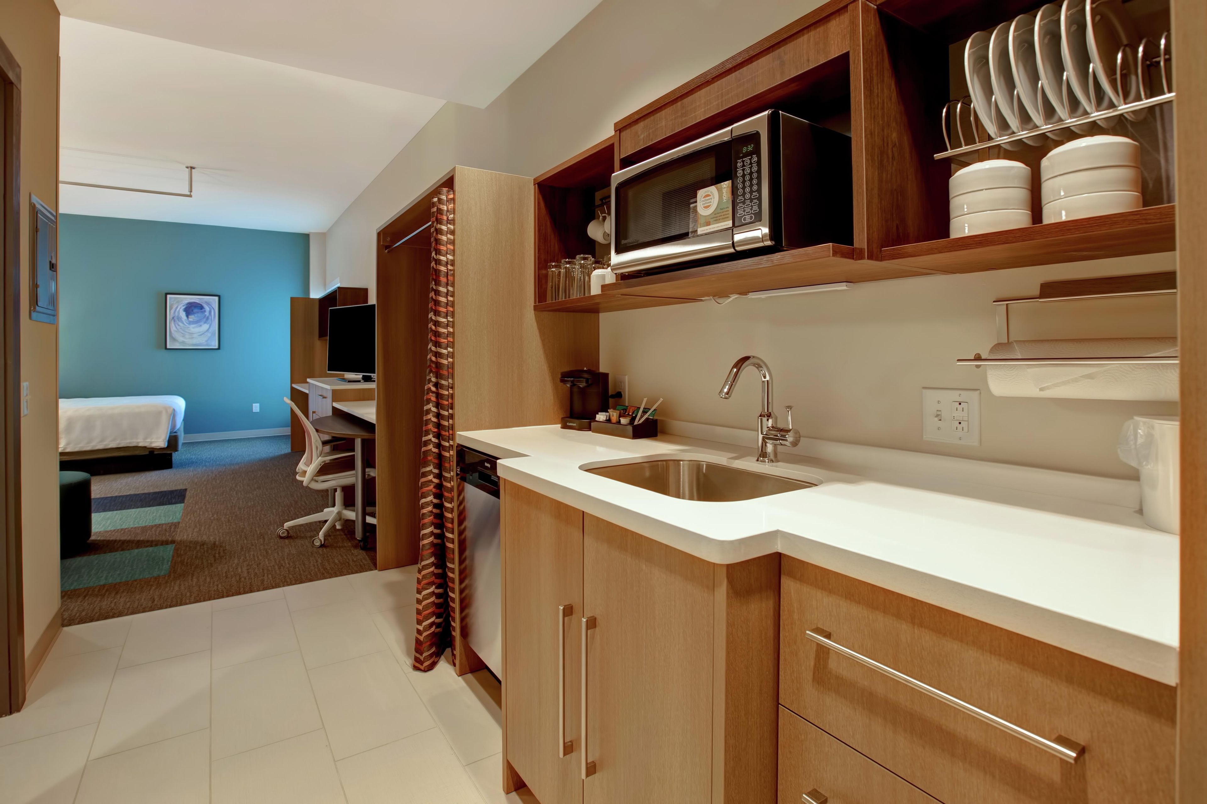 A modern kitchen with a built-in microwave, a sink, and wooden cabinets.