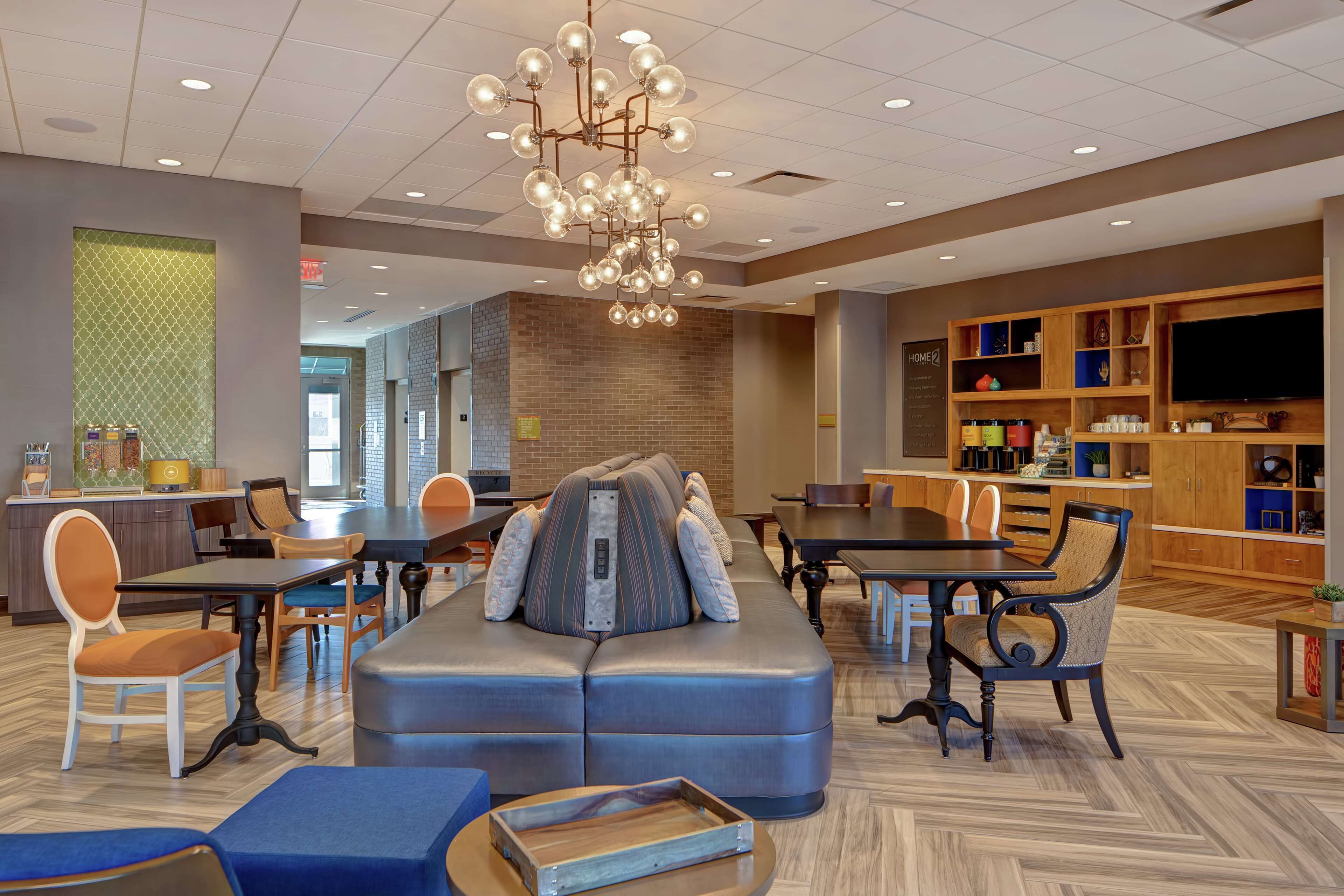 A modern hotel lobby with a seating area, a television, and a bar.