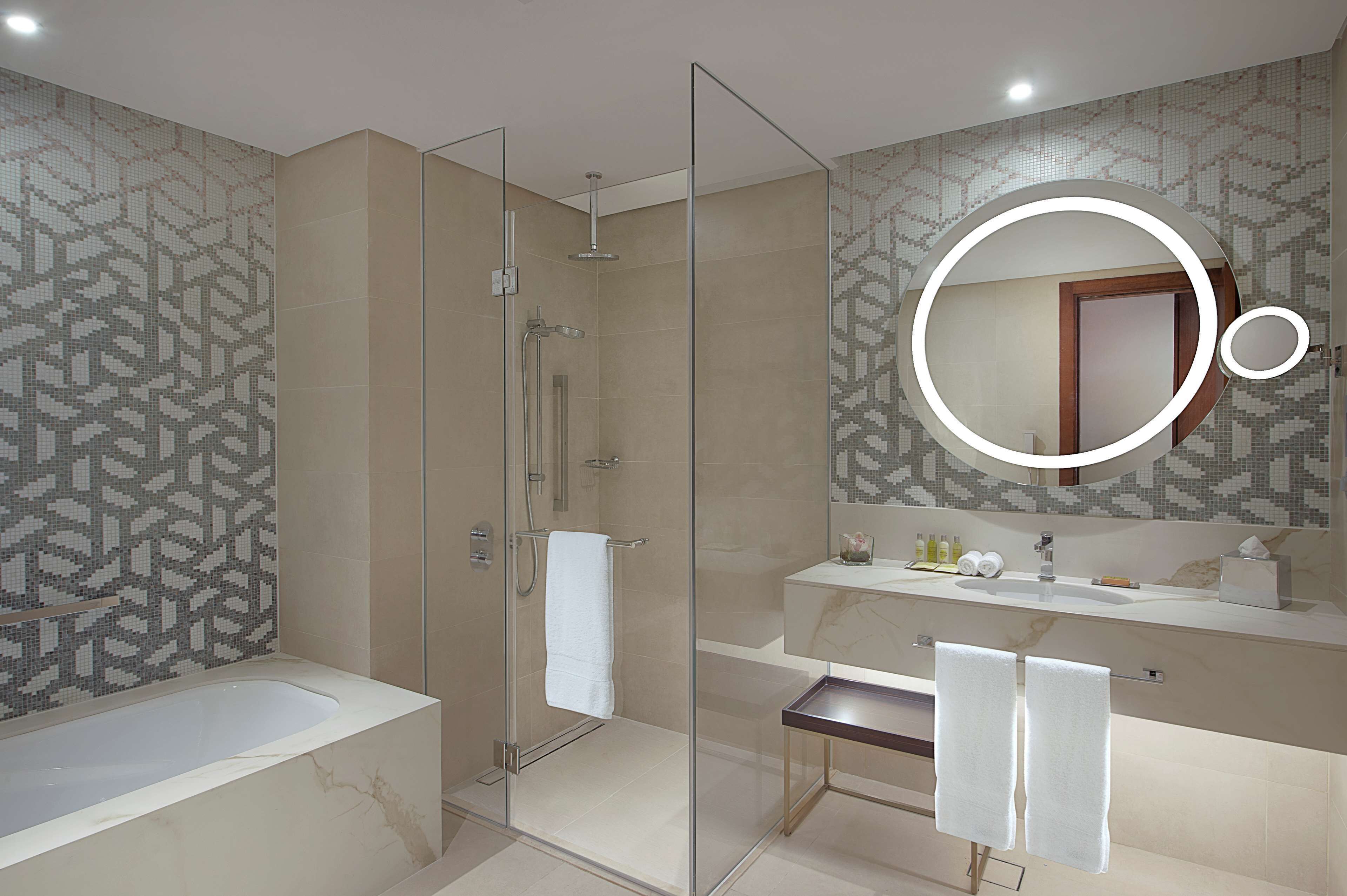 A modern bathroom with a glass-enclosed shower, a bathtub, and a vanity with a mirror.