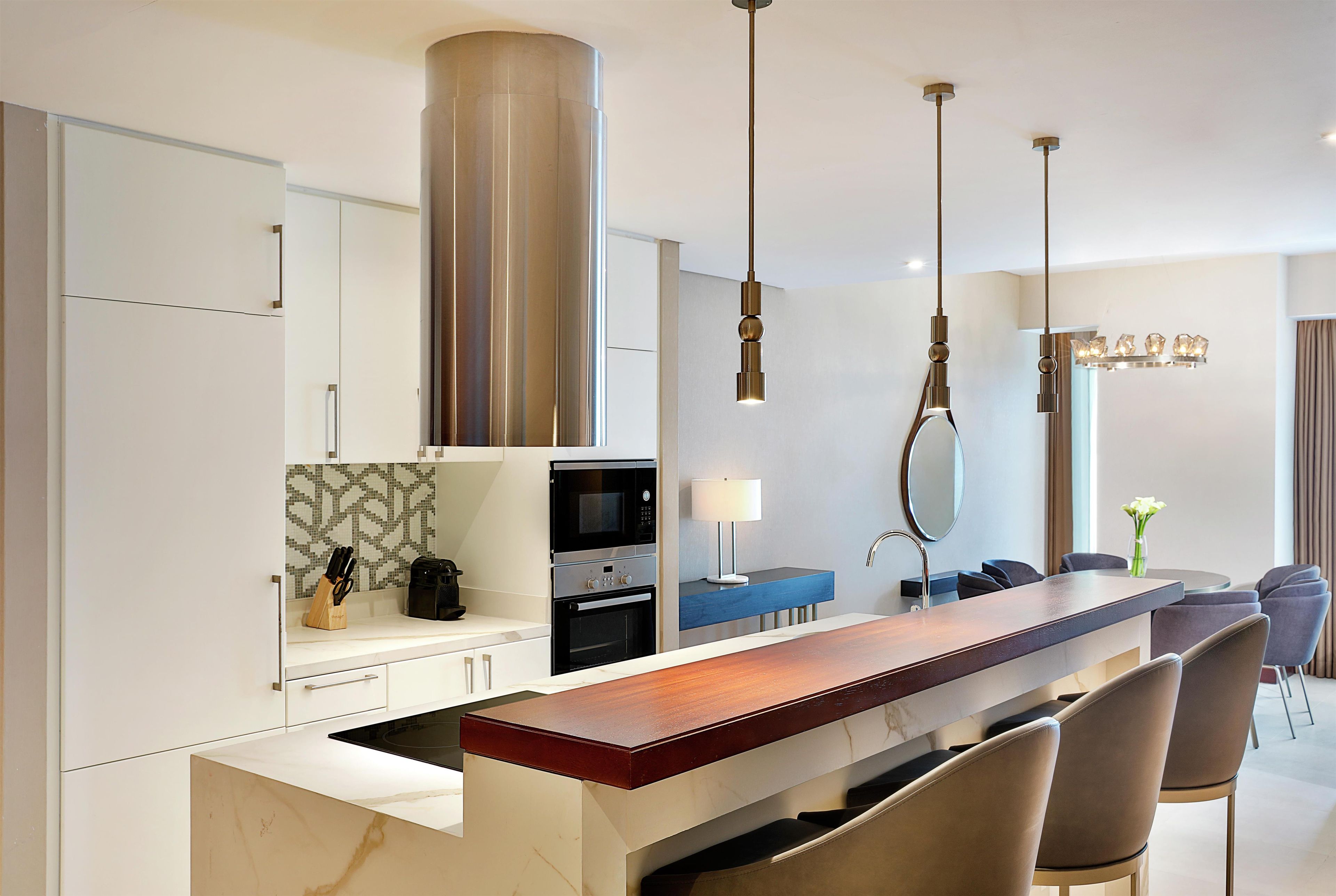 Una cocina moderna con una isla central, electrodomésticos integrados e iluminación contemporánea.