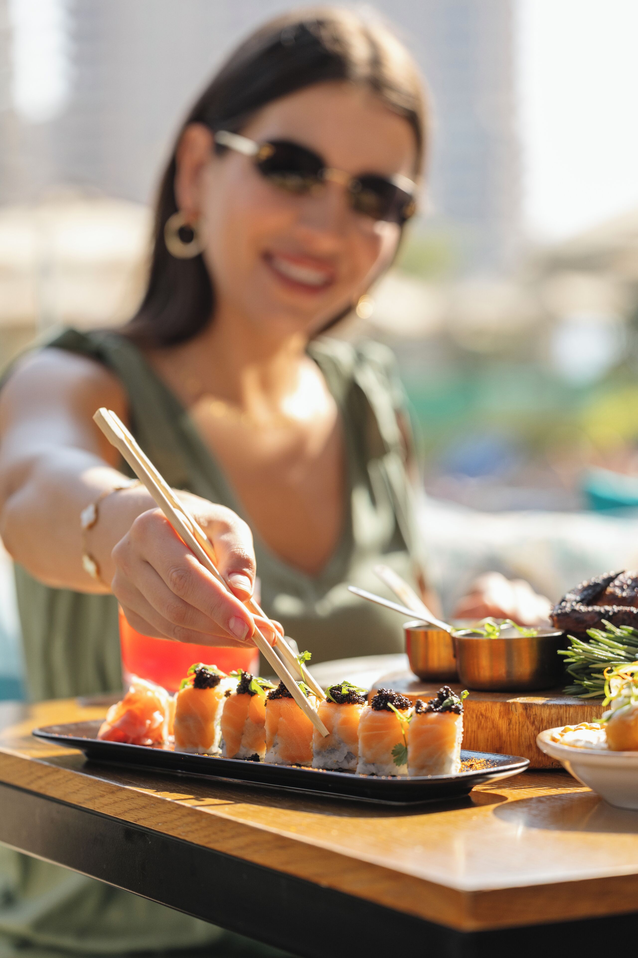 A person holding chopsticks over a plate of sushi.