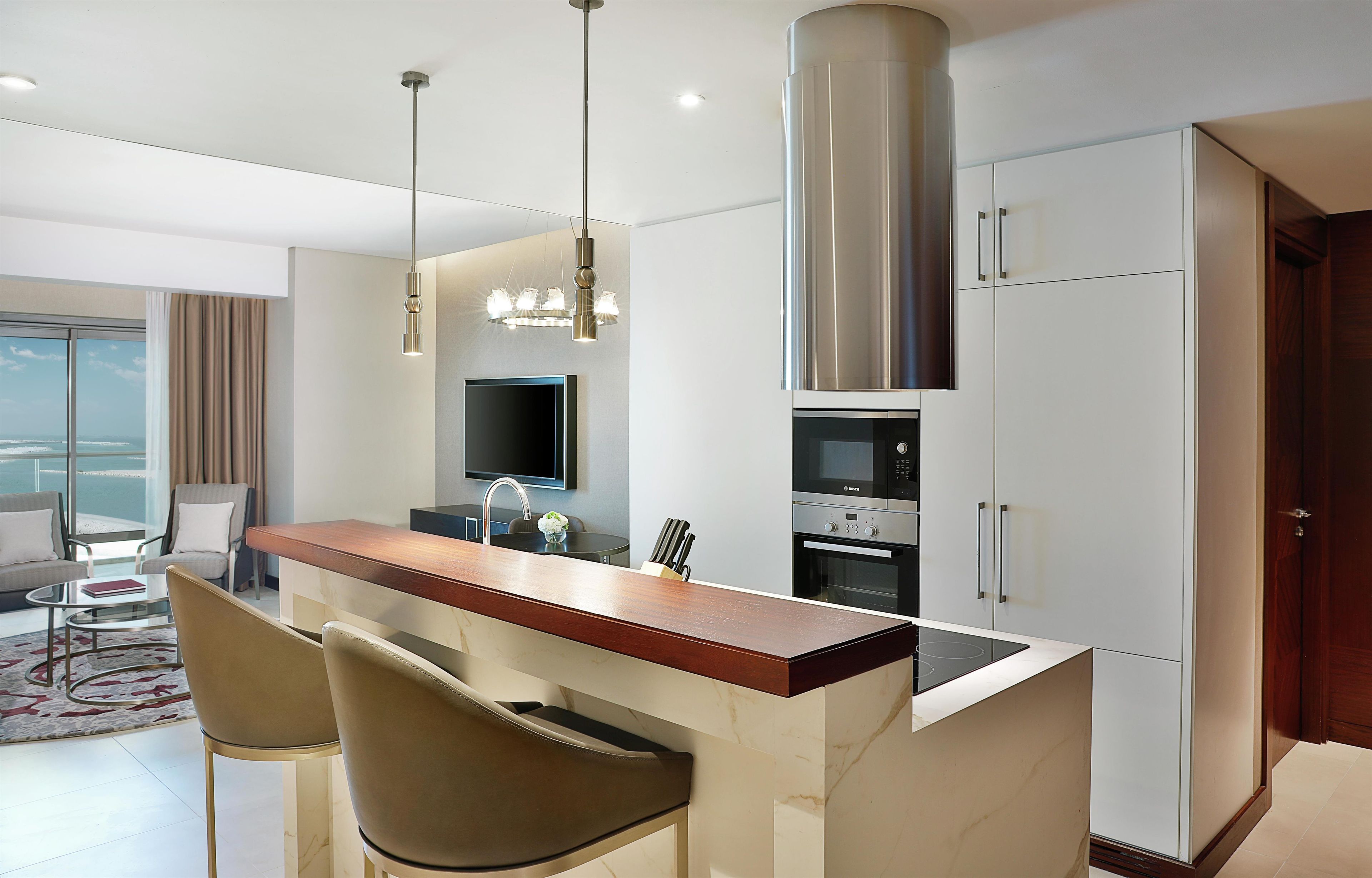A modern kitchen with a central island, stainless steel appliances, and a dining area with a view.