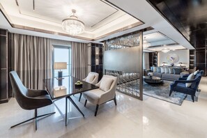 A modern living room with a glass coffee table, two armchairs, a sofa, and a chandelier. - Hilton Doha The Pearl (Doha)