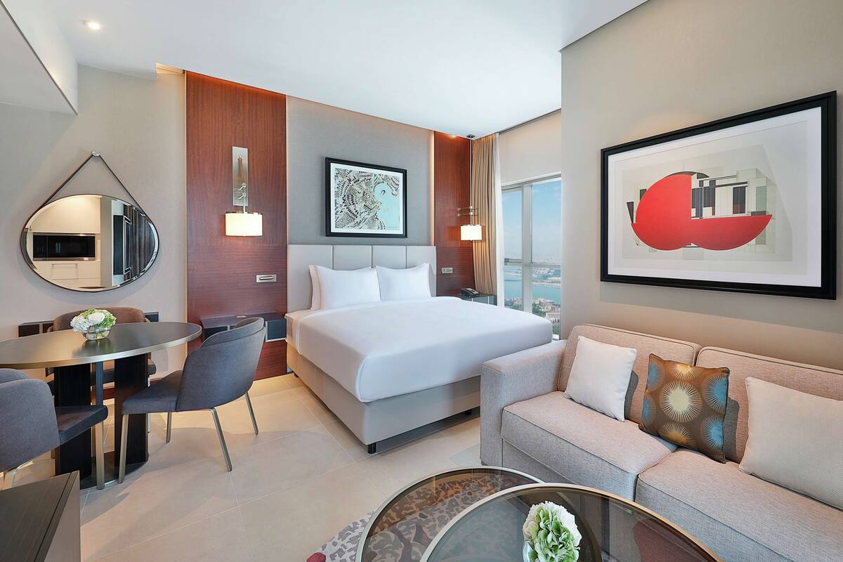 Une chambre d’hôtel moderne équipée d’un lit, d’un canapé, d’une table à manger et offrant une vue sur la ville.